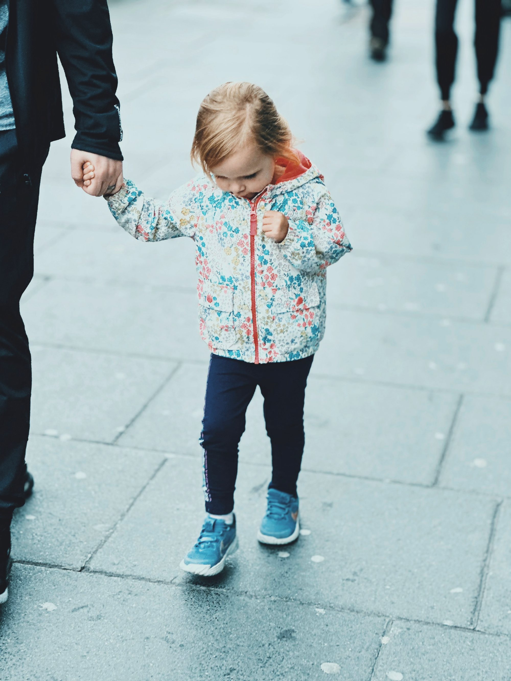 Un niño pequeño de la mano de un adulto en una calle de la ciudad